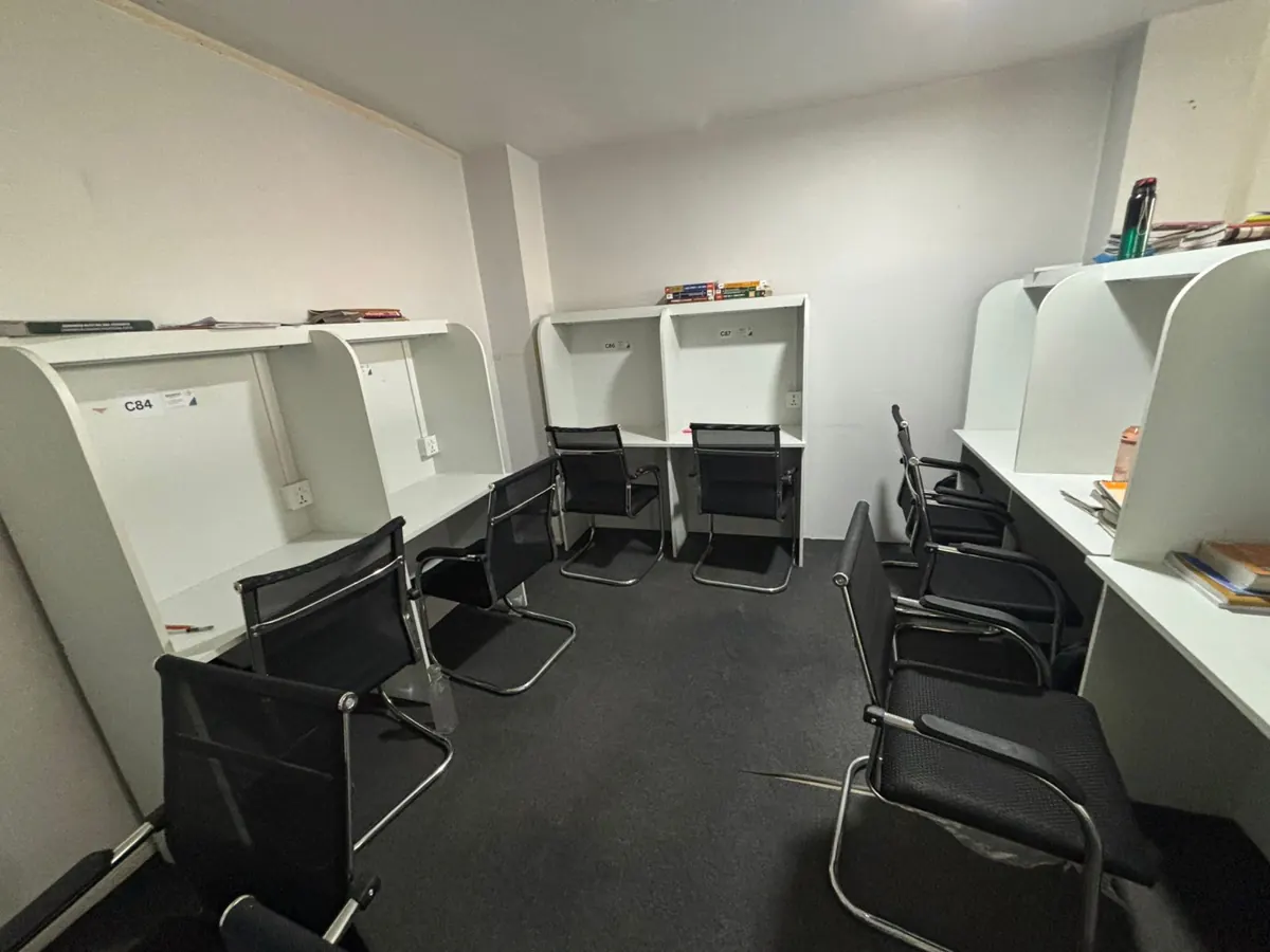A hall of white cabins with black mesh chairs.