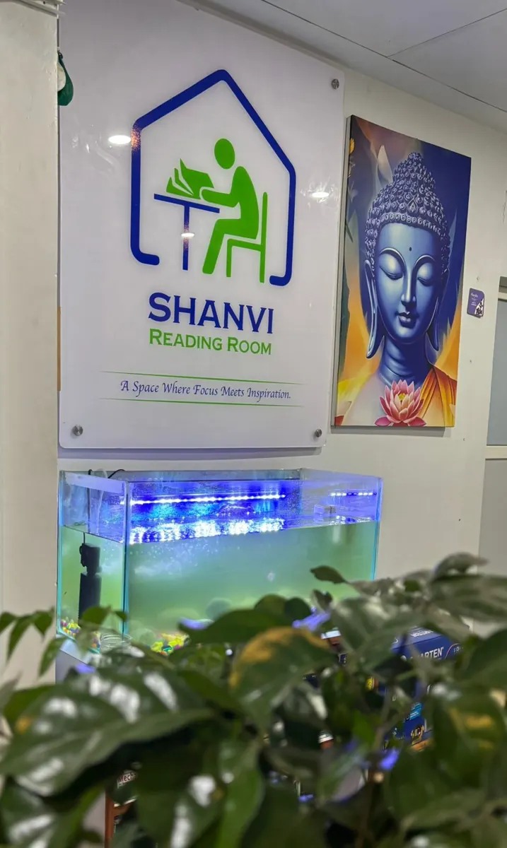 The Shanvi Reading Room logo on the wall beside a Buddha painting and a lit fish tank.